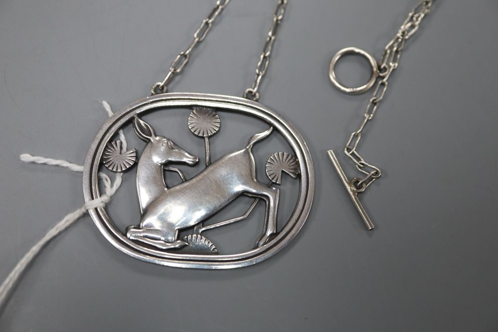 A Georg Jensen sterling kneeling deer oval pendant, no. 95, on white metal chain, 42mm gross 14.8 grams.